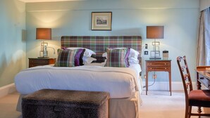 A hotel room with a large bed, two bedside tables, a chair, a desk, and a picture on the wall. - Chewton Glen Hotel and Spa (New Milton)
