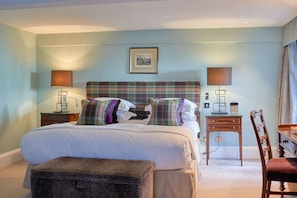 A hotel room with a large bed, two bedside tables, a chair, a desk, and a picture on the wall.