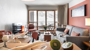 Ein modernes Wohnzimmer mit einer Couch, Sesseln, einem Couchtisch und einem Fernseher.
