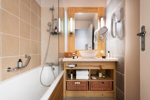 Un bagno con una vasca, un mobile bagno in legno con uno specchio e un portasacchi.