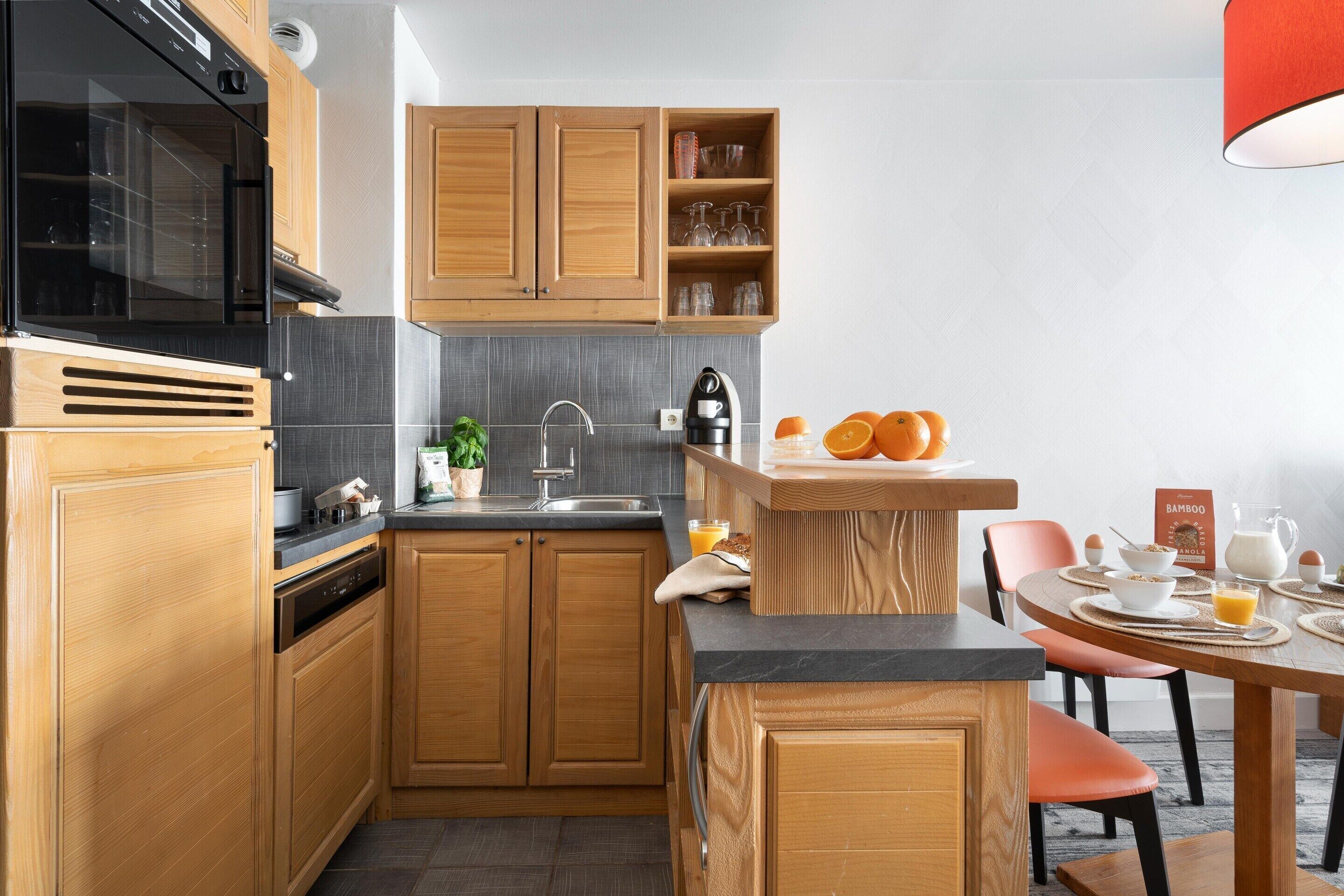 A kitchen with wooden cabinets, a black microwave, a sink, and a breakfast setup with orange juice and eggs.