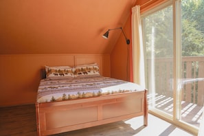 A bedroom with a wooden bed, a large window, and a view of a wooden deck.