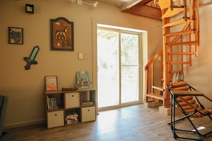 A room with a wooden staircase, a bookshelf, and a large window.