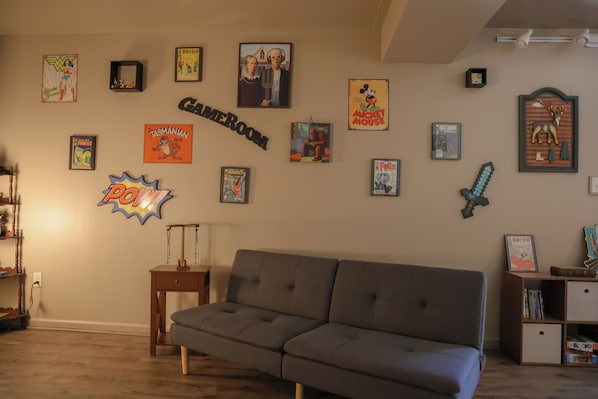 A living room with a grey sofa, a small wooden side table, and a bookshelf.