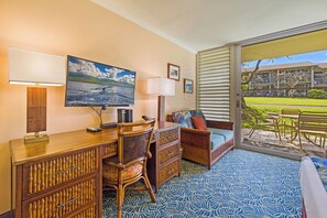 Ein Zimmer mit Schreibtisch, Stuhl, Sofa und einem großen Fenster mit Jalousien.