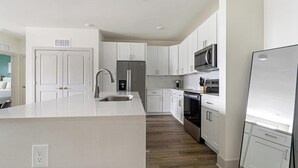 A modern kitchen with white cabinetry, stainless steel appliances, and a central island. - Landing | Stunning 3BD, Gym (Santa Rosa Beach)