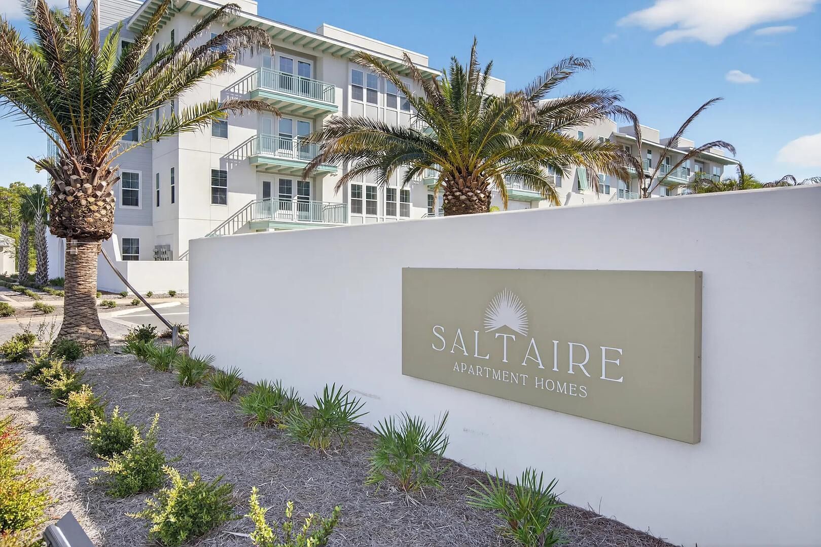 Ein Schild für SALTAIRE APARTMENT HOMES mit einem modernen Gebäude im Hintergrund.