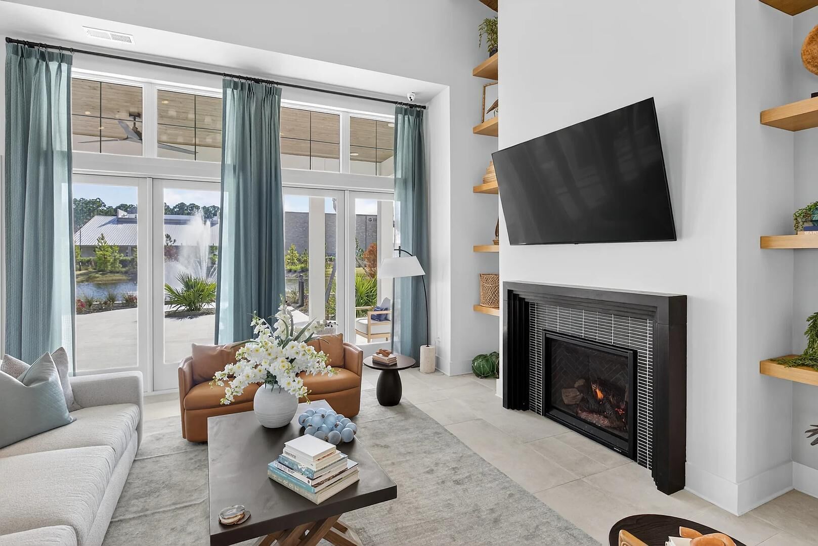 Een moderne woonkamer met een open haard, een flatscreen-tv en uitzicht op een meer.