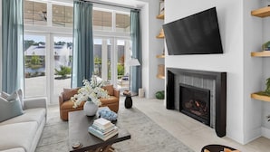 Una sala de estar moderna con chimenea, un televisor de pantalla plana y vista a un lago.