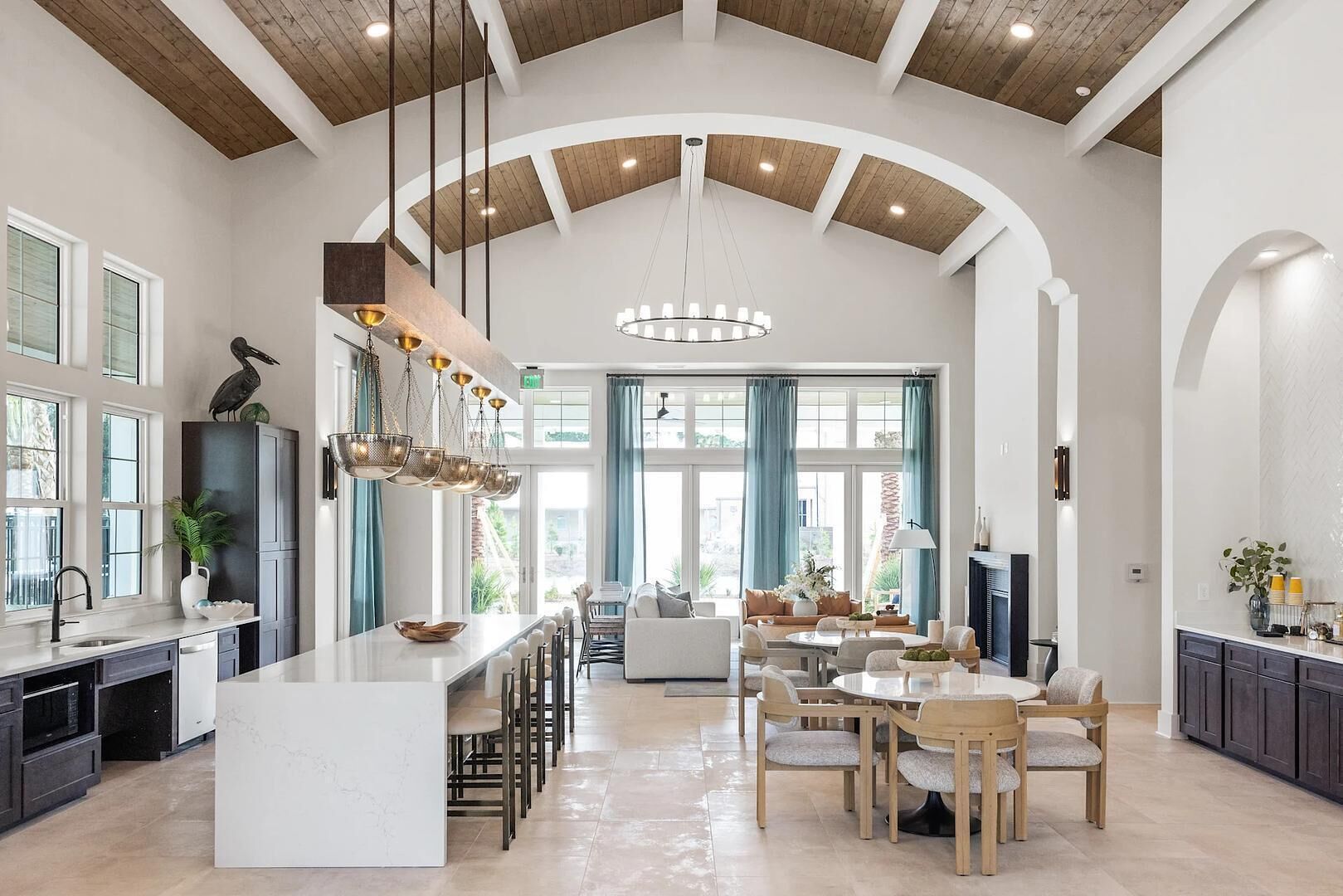 A spacious kitchen with a large island, modern pendant lighting, and a view to a dining area.