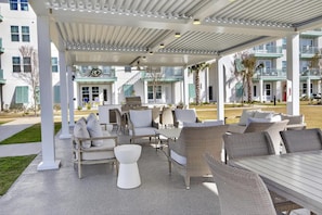 A covered outdoor seating area with wicker furniture and a grill. - Landing | Incredible 1BD, Gym (Santa Rosa Beach)