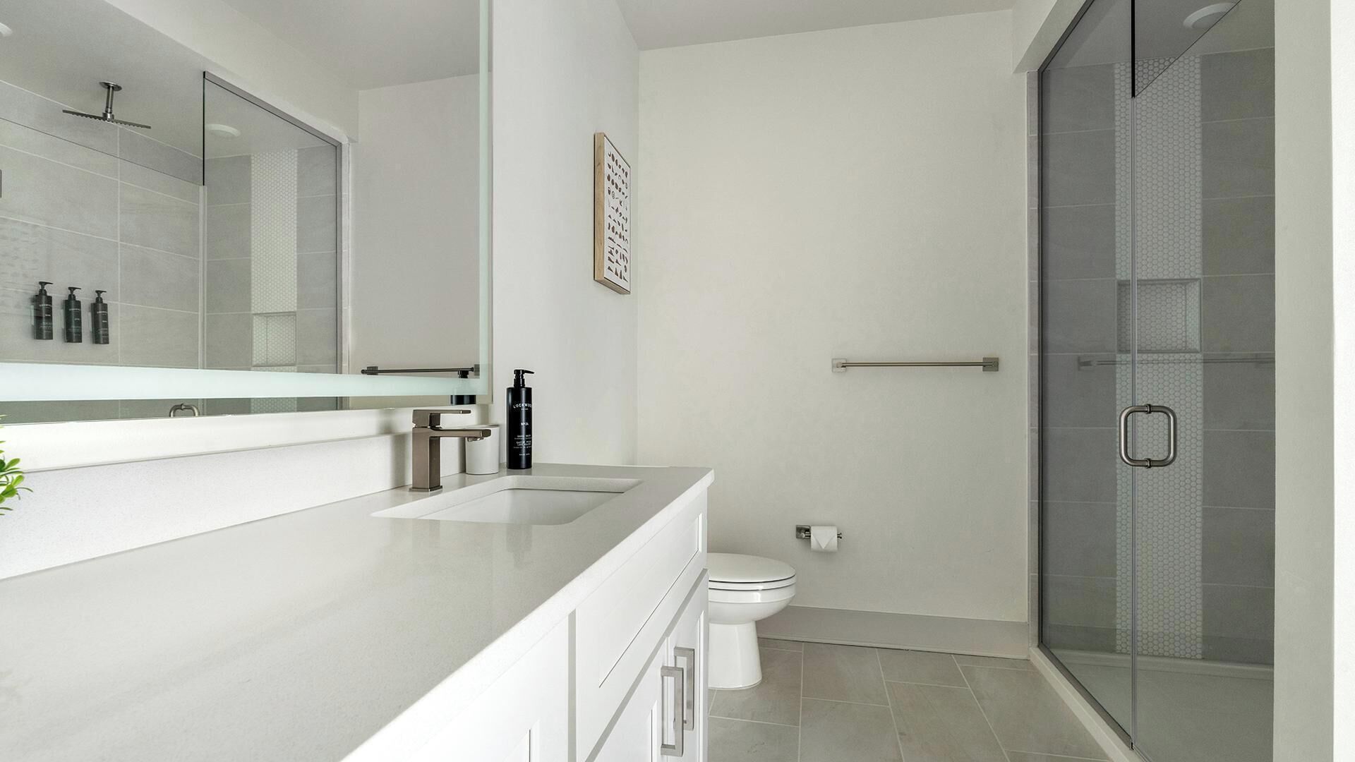 Ein modernes Badezimmer mit großem Spiegel, Toilette und Duschbereich.