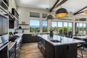 Una cocina moderna con una isla grande, electrodomésticos de acero inoxidable y vistas al exterior.