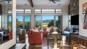 A spacious living room with a large sofa, a coffee table, and a fireplace. - Santa Fe Design Home · Stargazing Dome, Sauna, Cold Plunge & Mountain Views (Santa Fe)