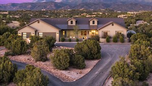 A modern two-story house with a driveway, surrounded by trees and mountains. - Santa Fe Design Home · Stargazing Dome, Sauna, Cold Plunge & Mountain Views (Santa Fe)