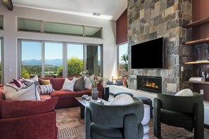 Una sala de estar moderna con chimenea, ventanas amplias y televisor de pantalla plana.