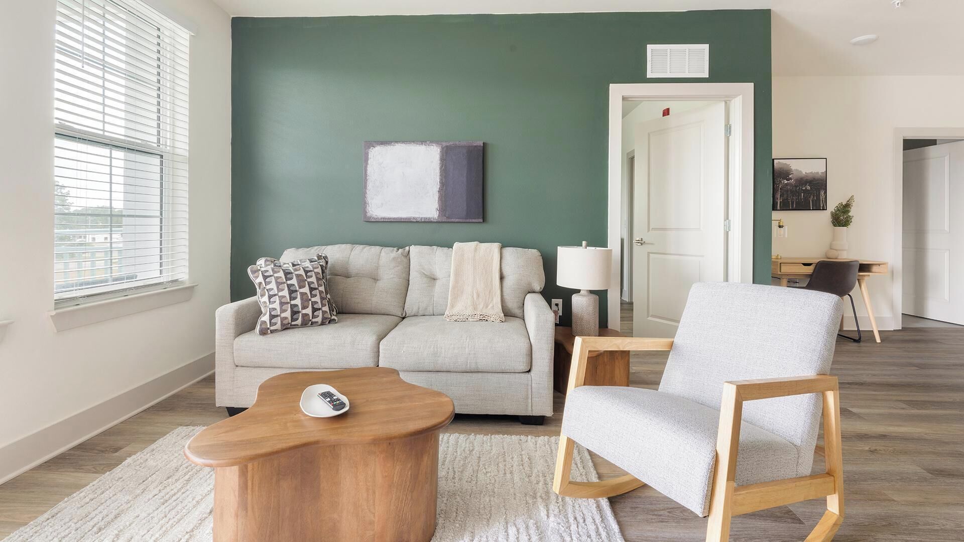 A living room with a sofa, armchair, coffee table, and a painting on the wall.