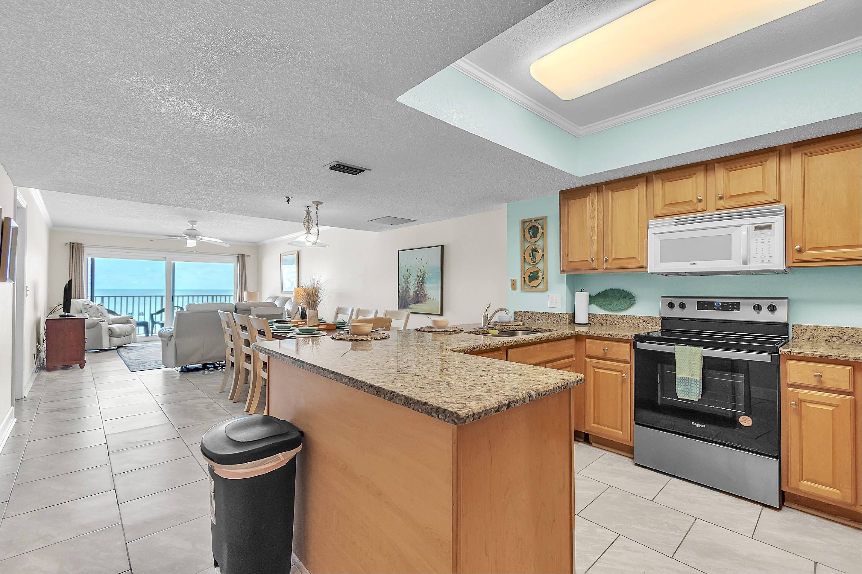 A spacious kitchen with granite countertops, wooden cabinets, a large island, and a stainless steel oven.