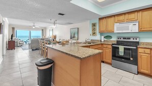 A spacious kitchen with granite countertops, wooden cabinets, a large island, and a stainless steel oven. - Direct Beachfront Condo with Amazing Gulf Views! Pool, Grill, Free Wi-Fi & Parking! ~ 204 Seagate (Indian Rocks Beach)