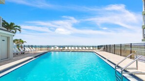 A swimming pool with lounge chairs and a metal railing, surrounded by a fence. - Direct Beachfront Condo with Amazing Gulf Views! Pool, Grill, Free Wi-Fi & Parking! ~ 204 Seagate (Indian Rocks Beach)