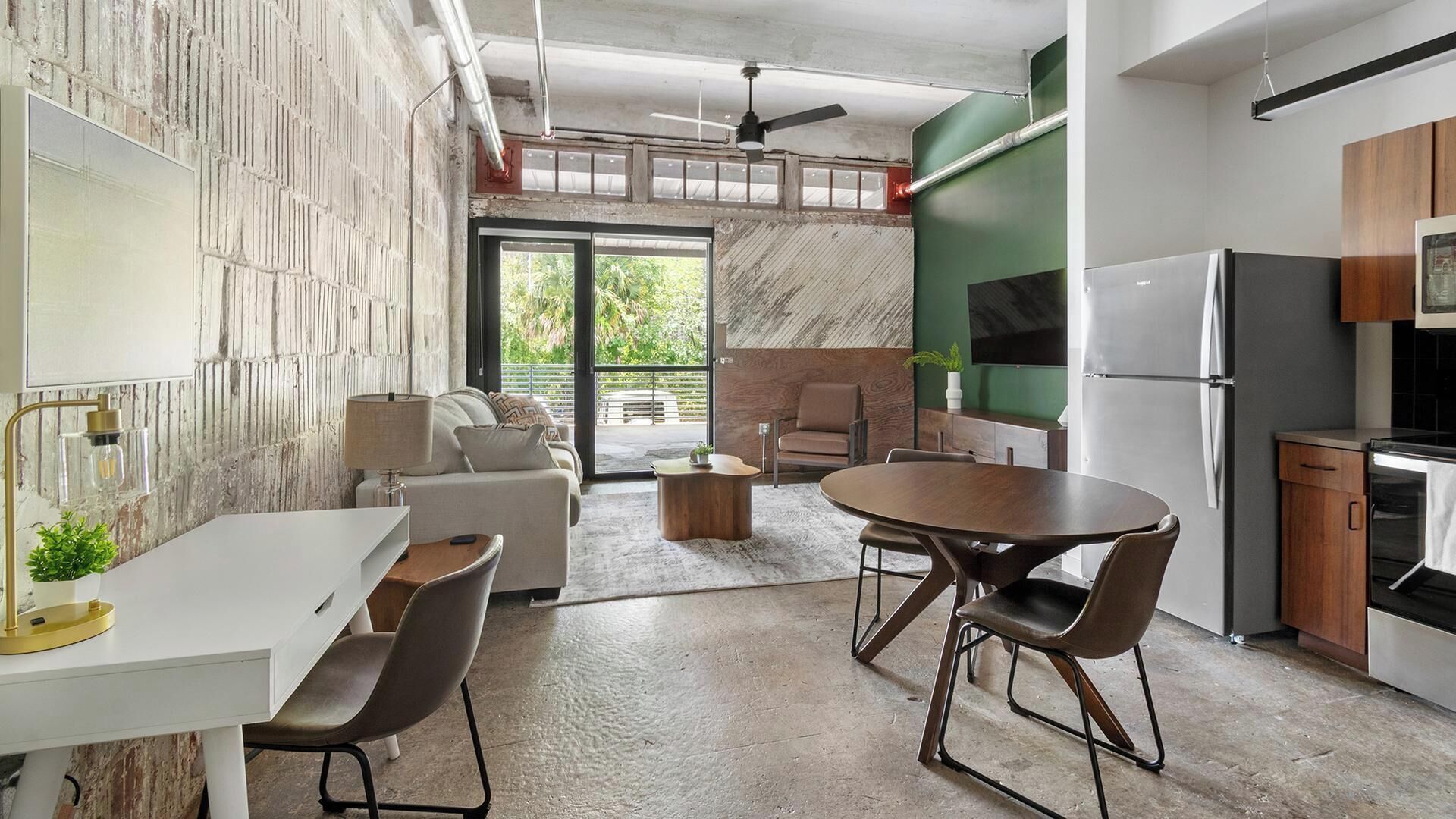 A modern kitchen with a dining area, a sofa, and a TV.