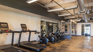 Una palestra con tapis roulant, cyclette ellittiche e attrezzi per sollevamento pesi.
