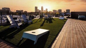 Una terrazza panoramica con poltrone e un tavolino, con vista sullo skyline cittadino al tramonto.