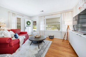 A living room with a red sofa, a round coffee table, a TV, and a view of the outdoors. - Midtown Luxury | 10 min to Ft. Benning (Columbus)