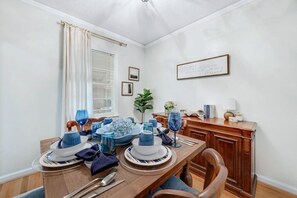 A dining room with a wooden table set for four, blue glassware, and a framed sign on the wall. - Midtown Luxury | 10 min to Ft. Benning (Columbus)