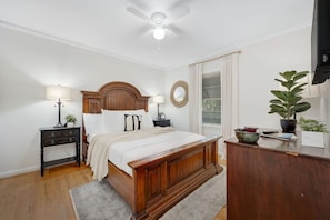A bedroom with a wooden bed, nightstands, a desk, a ceiling fan, and a window with curtains. - Midtown Luxury | 10 min to Ft. Benning (Columbus)