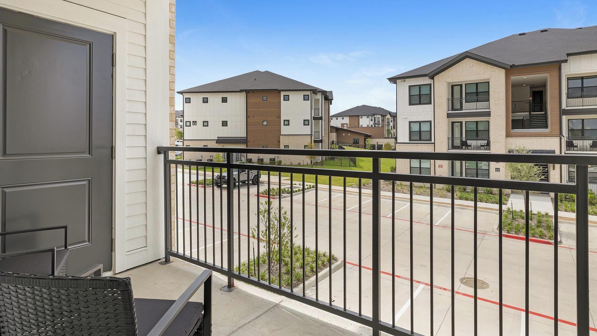 A residential building with a balcony, a parking lot, and neighboring houses.