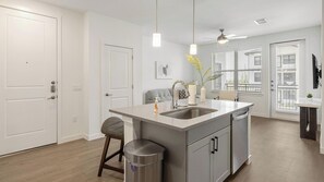 A modern kitchen with a central island, pendant lights, and a ceiling fan. - Landing | Amazing 1BD, Courtyard, Clubhouse (Dallas)