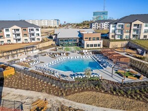 Ein moderner Apartmentkomplex mit einem zentral gelegenen Schwimmbad, Außenbereichen zum Sitzen und einem angelegten Garten.