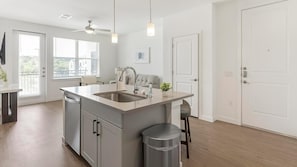 Eine moderne Küche mit einer zentralen Kochinsel, Deckenventilator und Blick ins Freie.