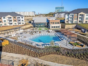 Complejo residencial con piscina, sillones de descanso y jardín ajardinado.