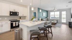 A modern kitchen with white cabinets, a black microwave, and a stainless steel range hood. - Landing | Amazing 2BD, Gym, Courtyard (Dallas)