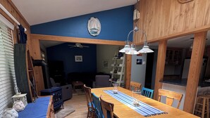 A dining area with a wooden table, chairs, a blue mat, and a skylight above.