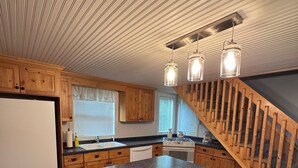 A kitchen with wooden cabinets, a granite countertop, a built-in stove, and a wooden staircase.