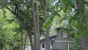 A house with a deck, surrounded by trees.