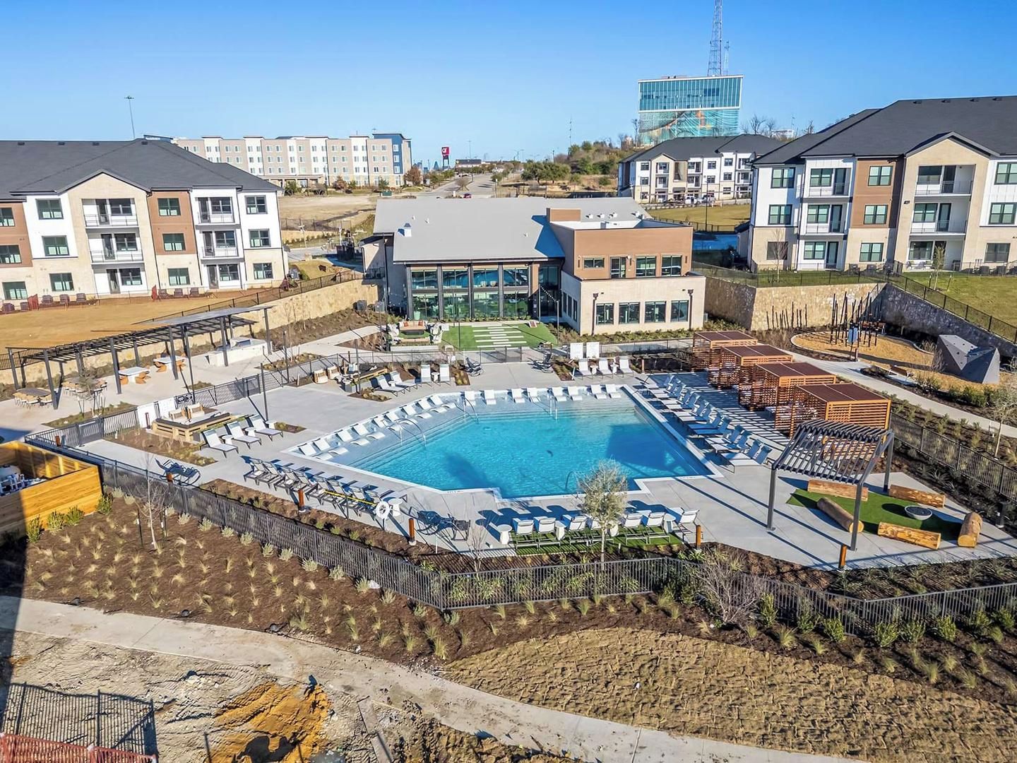 A residential complex with a swimming pool, lounge chairs, and a landscaped garden area.