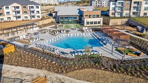 Un complesso residenziale moderno con piscina centrale, aree relax all'aperto e giardino curato.