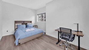 A bedroom with a bed, a desk, and a chair. - 105-Urban Retreat / Stylish-brand-new modern home (Calgary)