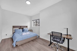 Ein Schlafzimmer mit Bett, Schreibtisch und Stuhl.
