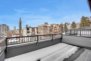 Ein Balkon mit Blick auf Wohnhäuser, einem Metallgeländer und Schnee auf dem Boden.