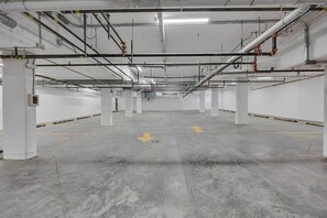 Sisätiloissa sijaitseva pysäköintihalli, jossa on betonilattiat, valkoiset seinät ja useita pylväitä.
