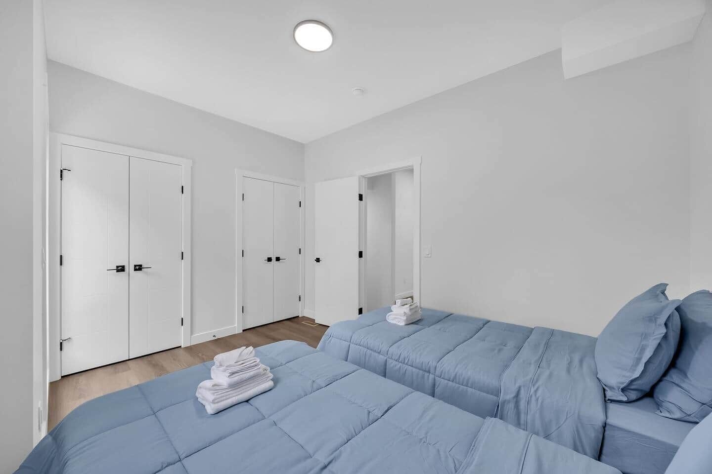 Ein Schlafzimmer mit zwei Betten, weißen Wänden und einem Holzboden.