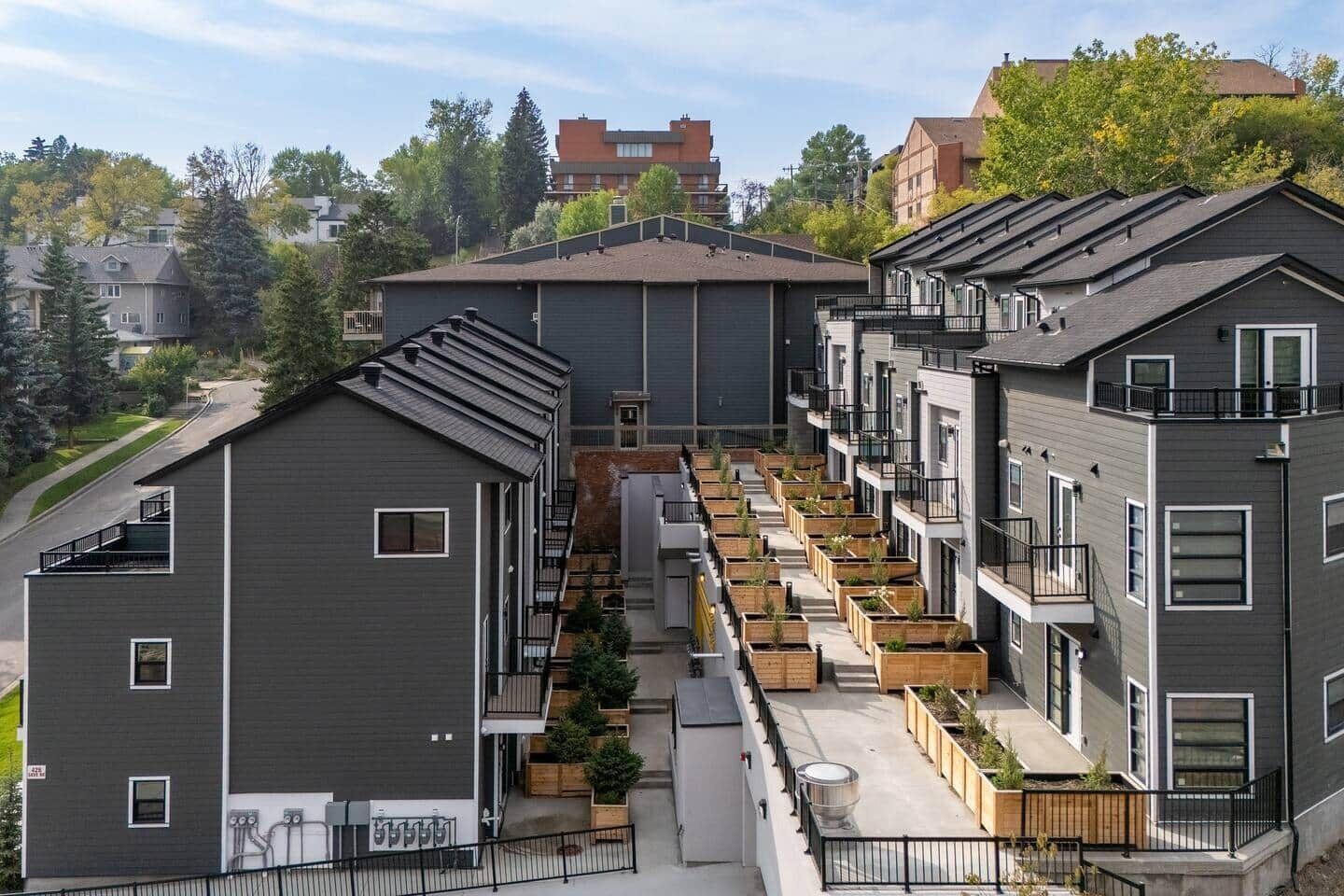 Ein moderner Wohnkomplex mit mehreren Wohnungen, Außenpflanzgefäßen und einem Innenhof.