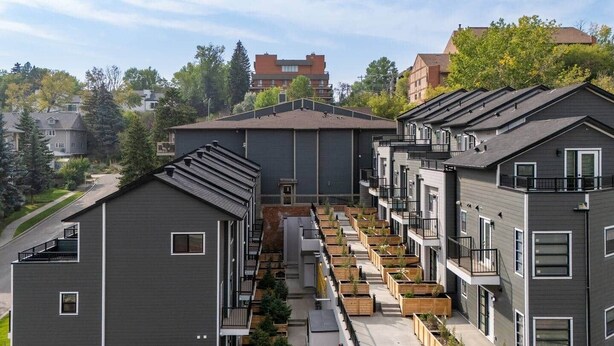 A modern apartment complex with multiple units, outdoor planters, and a central courtyard. - 105-Urban Retreat / Stylish-brand-new modern home (Calgary)