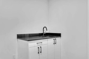 A kitchen with a black countertop, a faucet, and white cabinets. - 105-Urban Retreat / Stylish-brand-new modern home (Calgary)