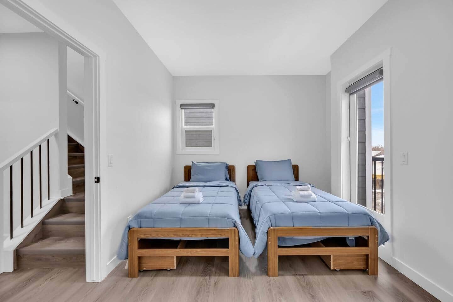 Ein Zimmer mit zwei Betten, einer Treppe und einem Fenster.